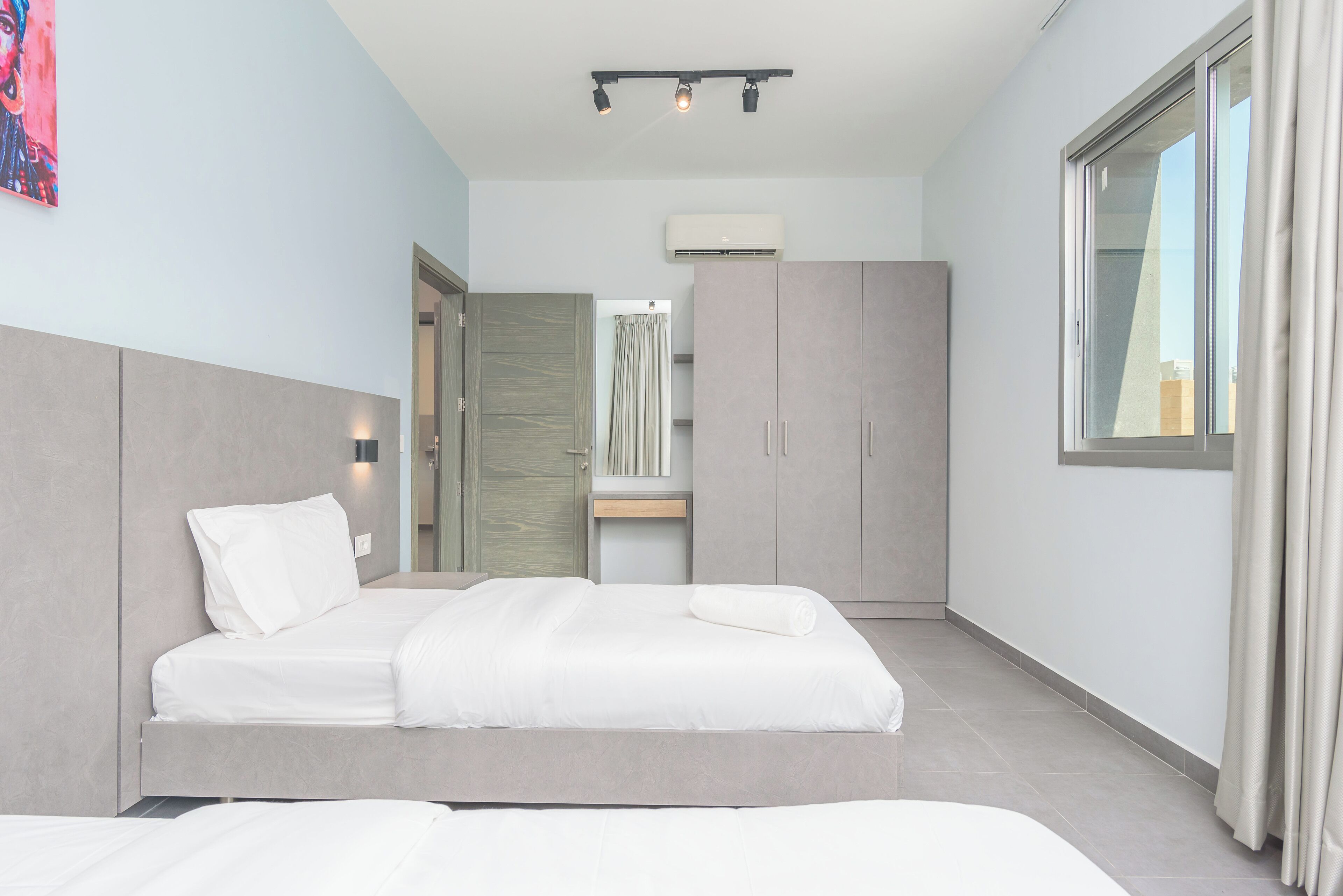 Una habitación de hotel moderna con una cama grande, un armario y una ventana con cortinas.