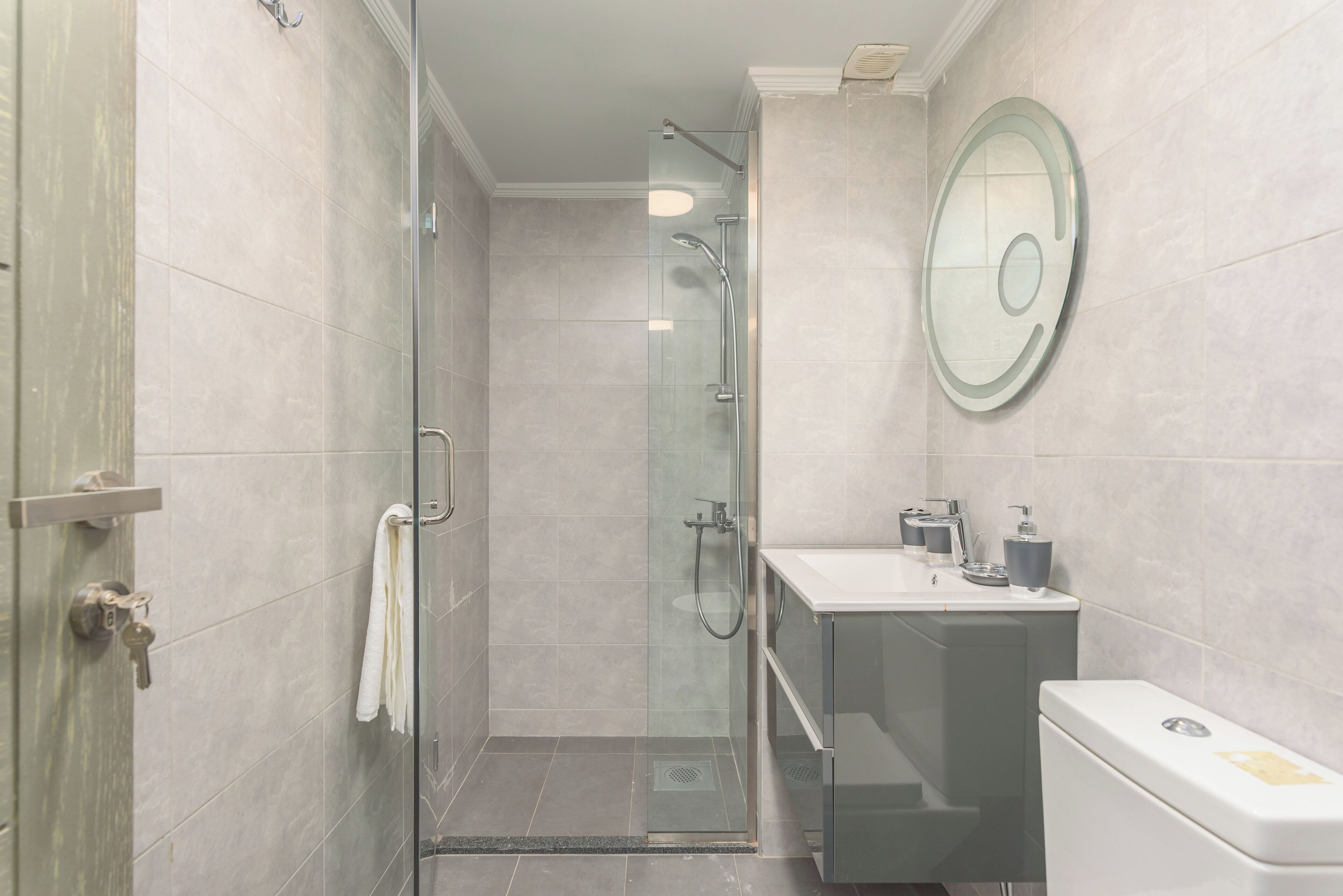 Un baño moderno con ducha de vidrio, un lavamanos blanco y un inodoro.