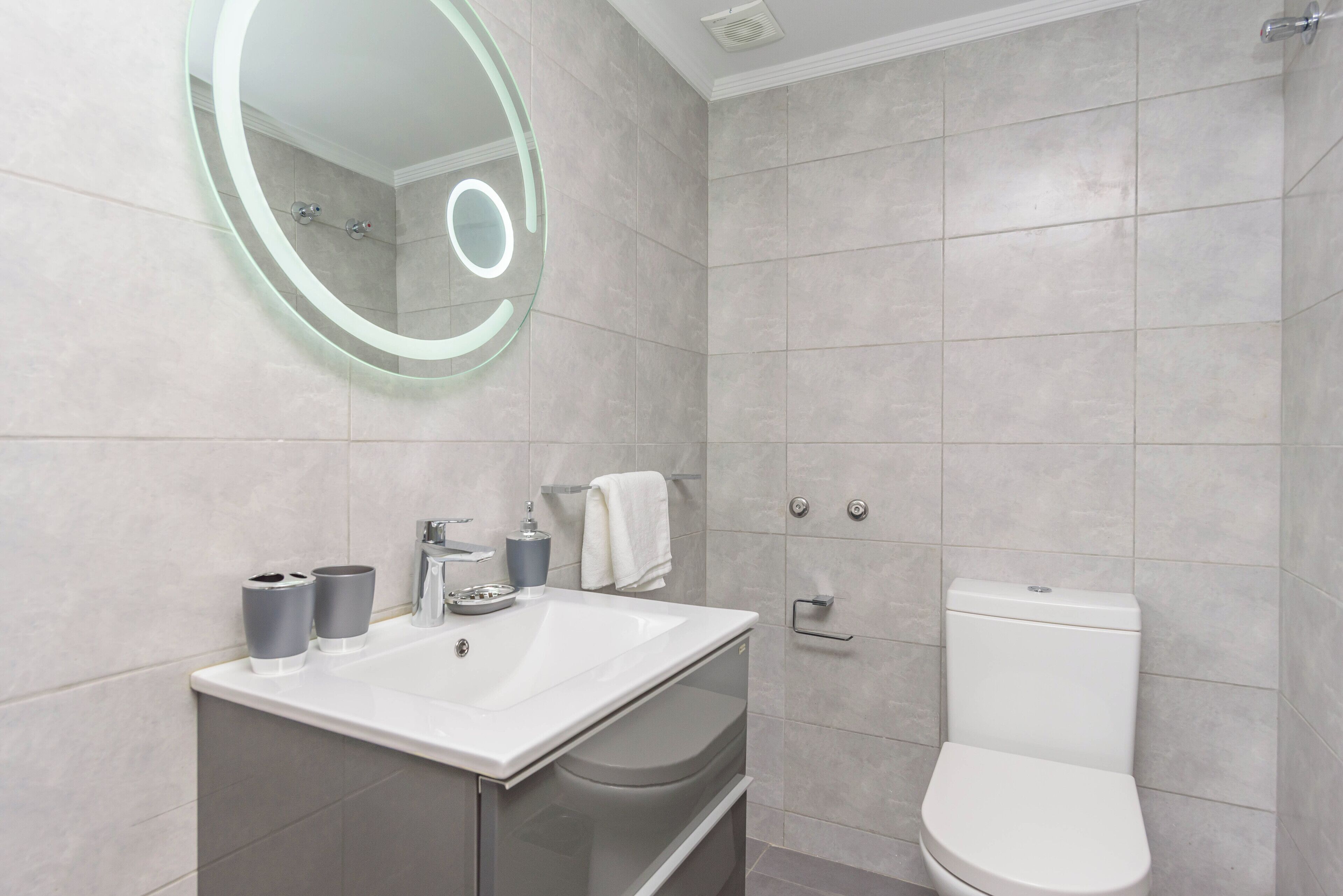 Une salle de bain moderne avec un lavabo blanc, un miroir et des toilettes.
