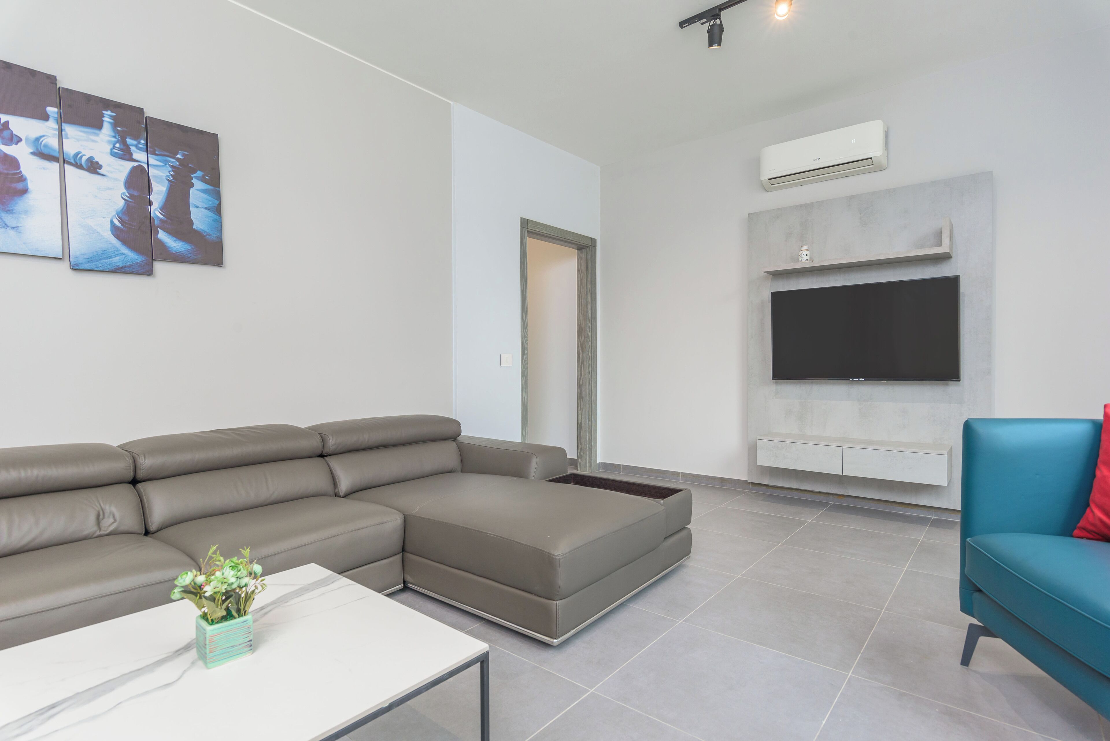 Una sala de estar moderna con un sofá seccional, un televisor de pantalla plana y una mesa de centro.