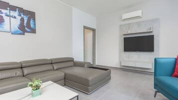 Una sala de estar moderna con un sofá seccional, un televisor de pantalla plana y una mesa de centro.