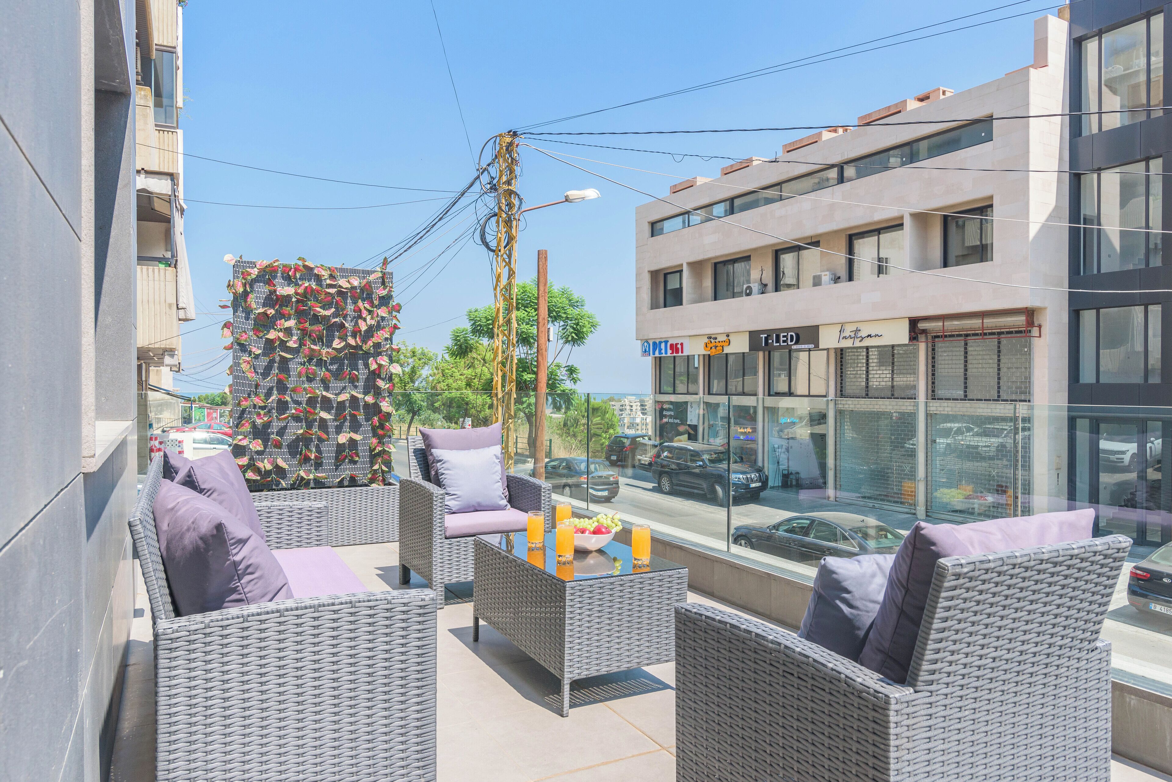 An outdoor seating area with wicker furniture and a table with fruit and drinks.