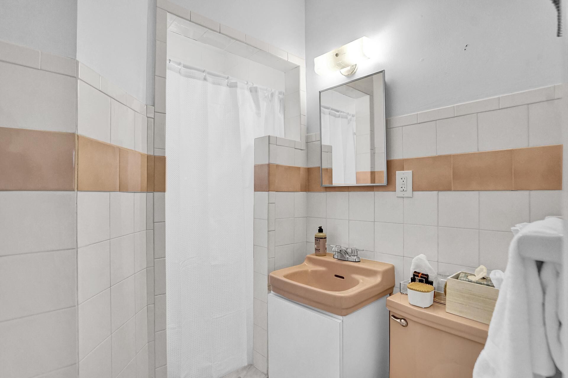 A bathroom with a shower, a sink, a mirror, and a towel rack.