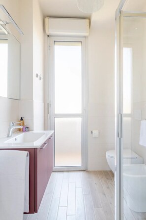 A modern bathroom with a glass shower enclosure, a white sink, and a toilet. - Appartamento Michelagelo (Prato)