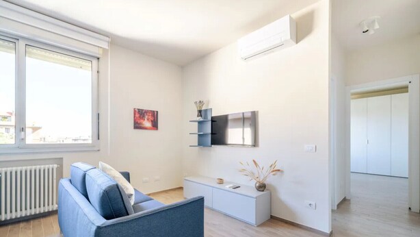 Un salon moderne avec un canapé bleu, une console blanche et un téléviseur fixé au mur.