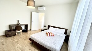 Une chambre d’hôtel équipée d’un lit, d’un bureau, d’une chaise, d’une lampe et d’un appareil de climatisation.
