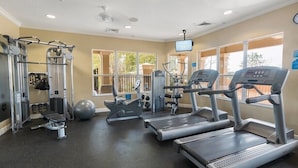 Een fitnessruimte met loopbanden, krachttoestellen en een hometrainer.