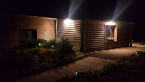 A modern building with two illuminated windows and a pathway leading to it.