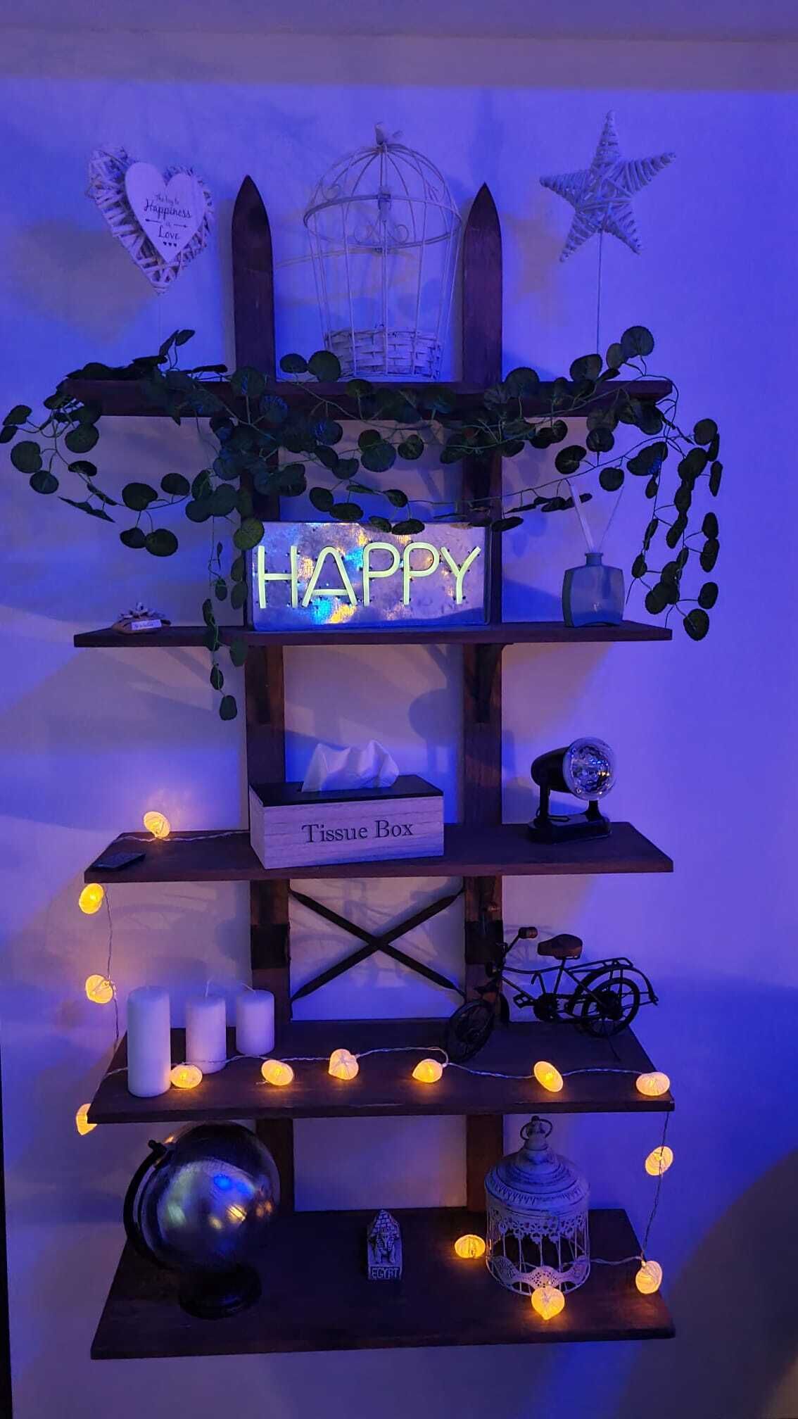 A shelf with a 'HAPPY' sign, a tissue box, candles, and decorative items.