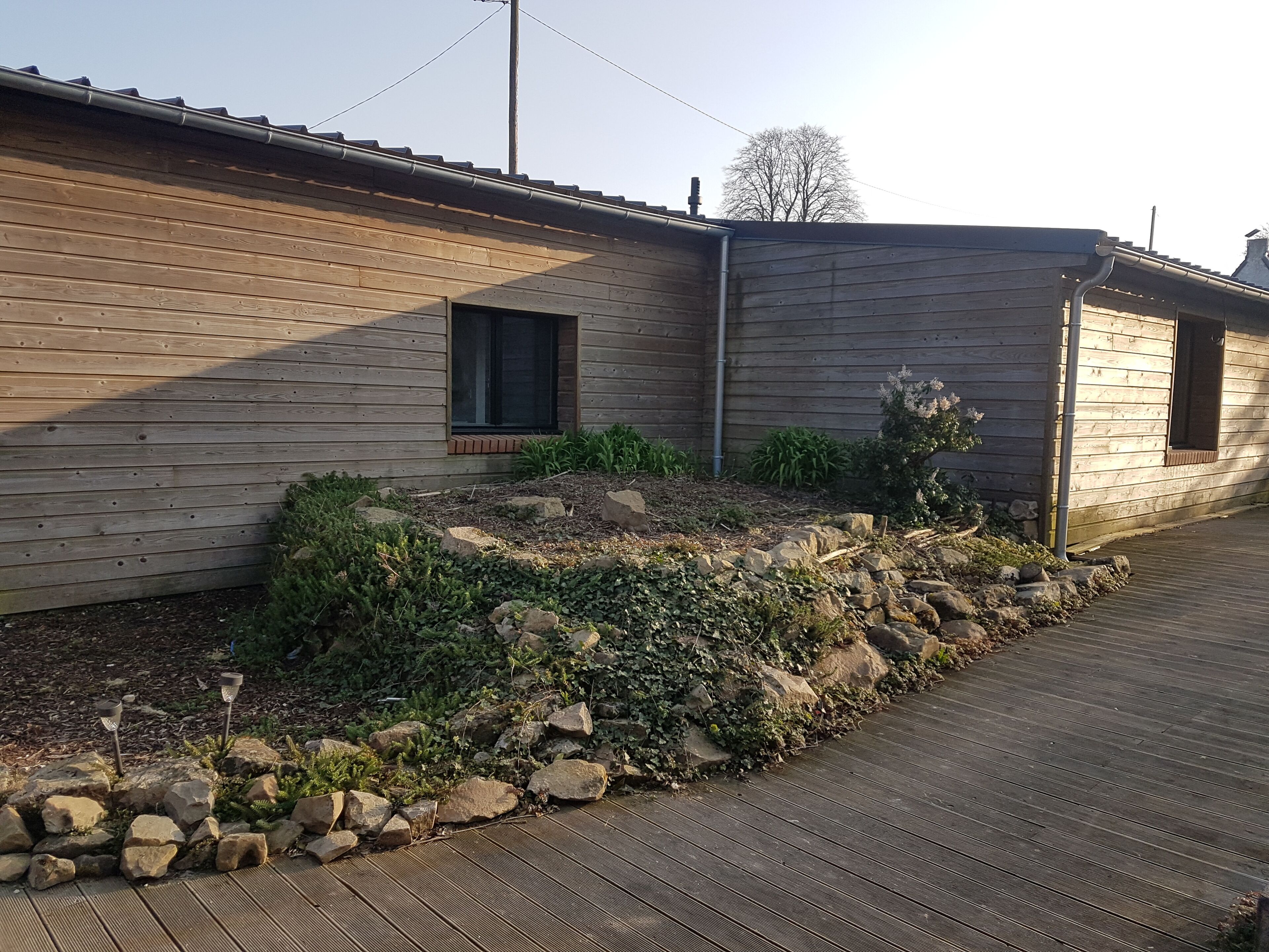 A wooden cabin with a sloped roof, a small window, and a stone pathway leading to the entrance.