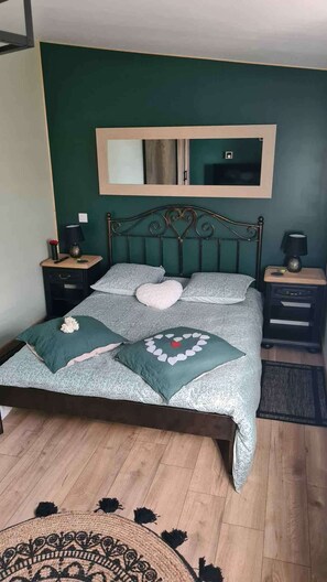 A bedroom with a bed, two nightstands, a mirror, and a wooden floor.