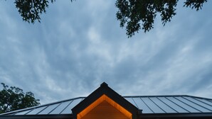 Een houten terras dat leidt naar een gebouw met een donkere gevel en een verlichte ingang.