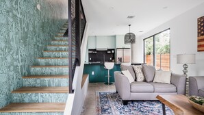 Een modern interieur met een trap, een keuken, een zithoek met een bank en een kamerbreed tapijt.