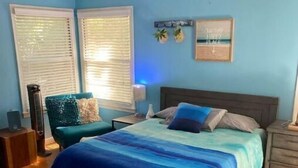 Ein Schlafzimmer mit Bett, Nachttisch, Sessel und Deckenventilator.