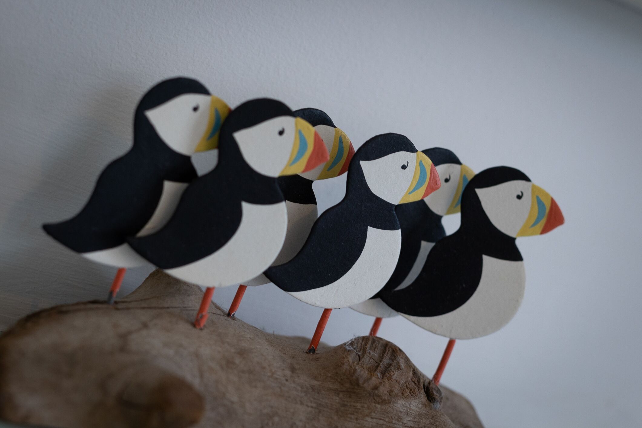 Eine Reihe von Pinguinen aus Papier, die an Holzästen befestigt sind.