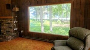 A room with a large window, a fireplace, and a chair. - West Bay House Private Frontage in Traverse City (Traverse City)