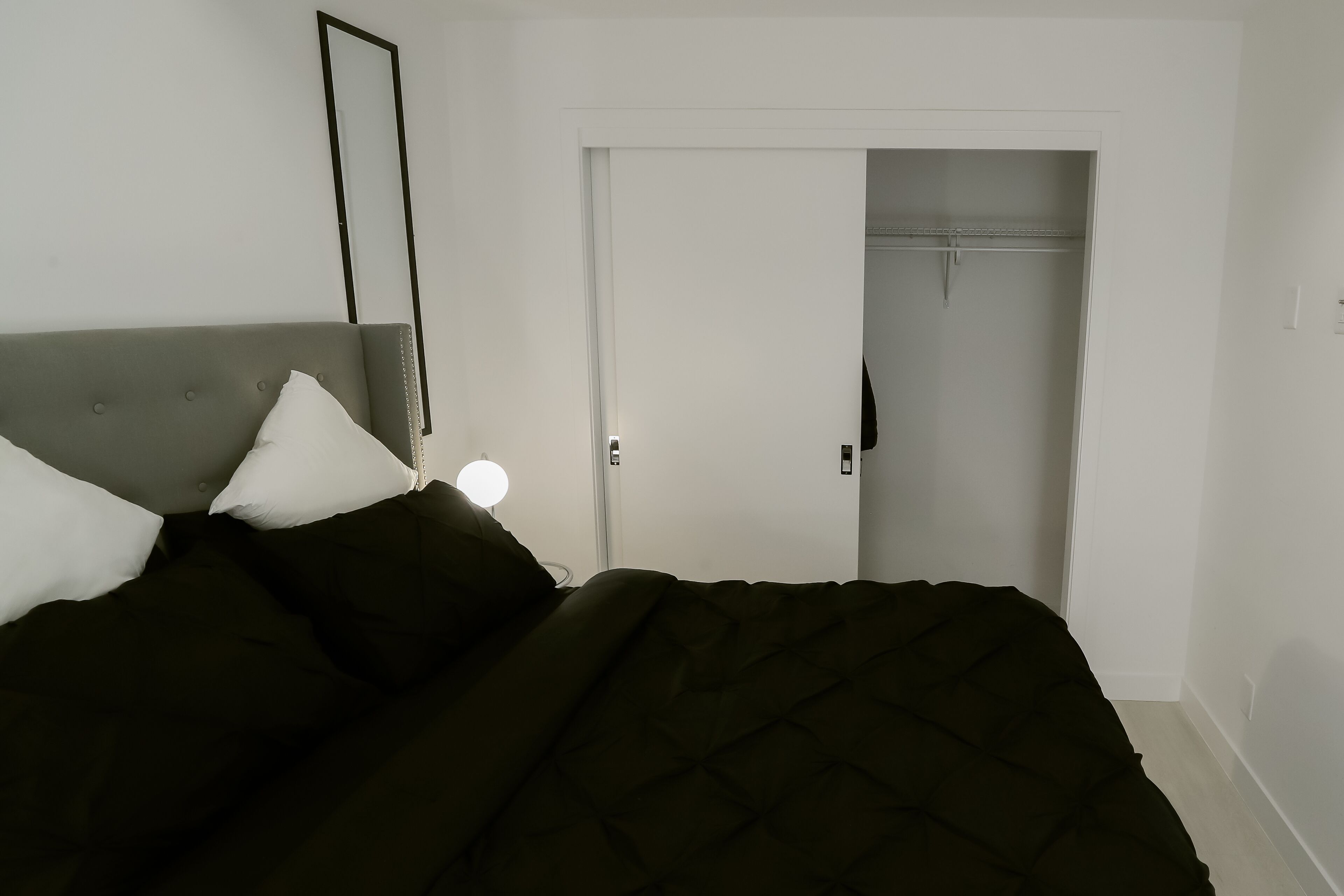 Um quarto com uma cama, abajur e guarda-roupa.