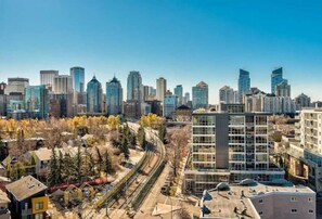 A cityscape with modern high-rise buildings, a railway track, and a mix of residential and commercial structures. - ✨ Stylish Walkout Condo in the Heart of Trendy Kensington ✨ (Calgary)