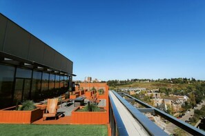 A modern building with a glass facade and a rooftop terrace with seating and planters. - ✨ Stylish Walkout Condo in the Heart of Trendy Kensington ✨ (Calgary)