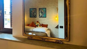 A bedroom with a large mirror, a bed with pillows, and two wall-mounted artworks.