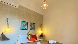A bedroom with a large bed, a hanging light fixture, two wall-mounted lamps, and two framed artworks.
