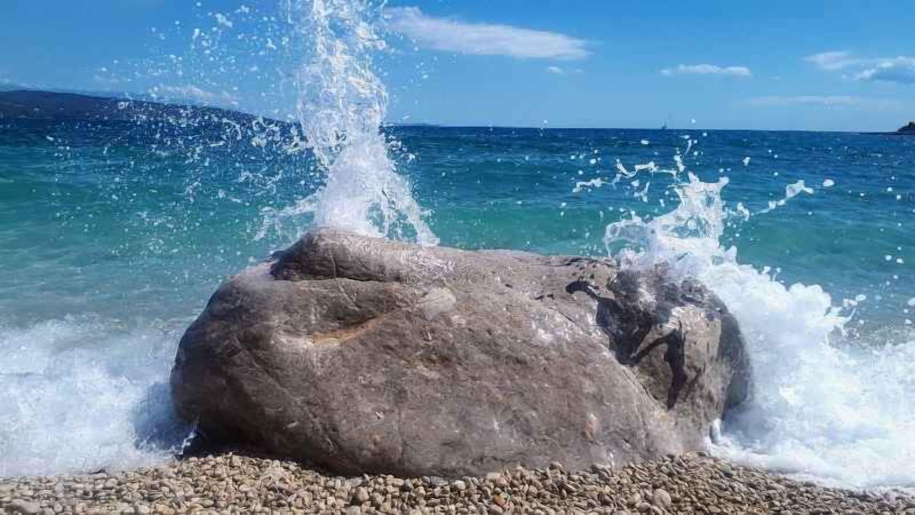 Una gran roca con agua salpicando a su alrededor.