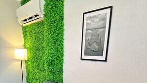 Un salon moderne avec un canapé gris, un mur vert et un tableau encadré.