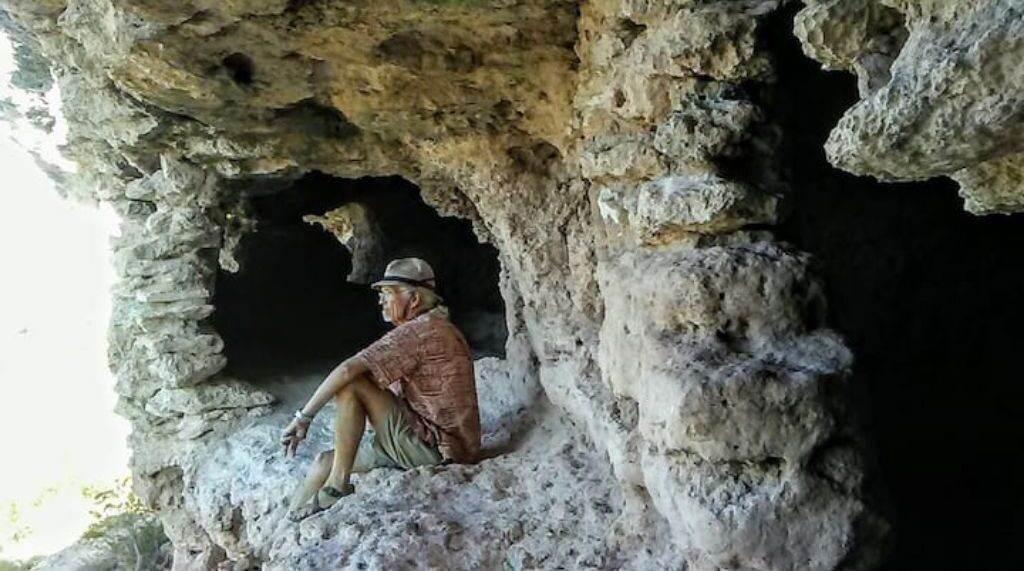 A person sitting inside a cave-like structure.