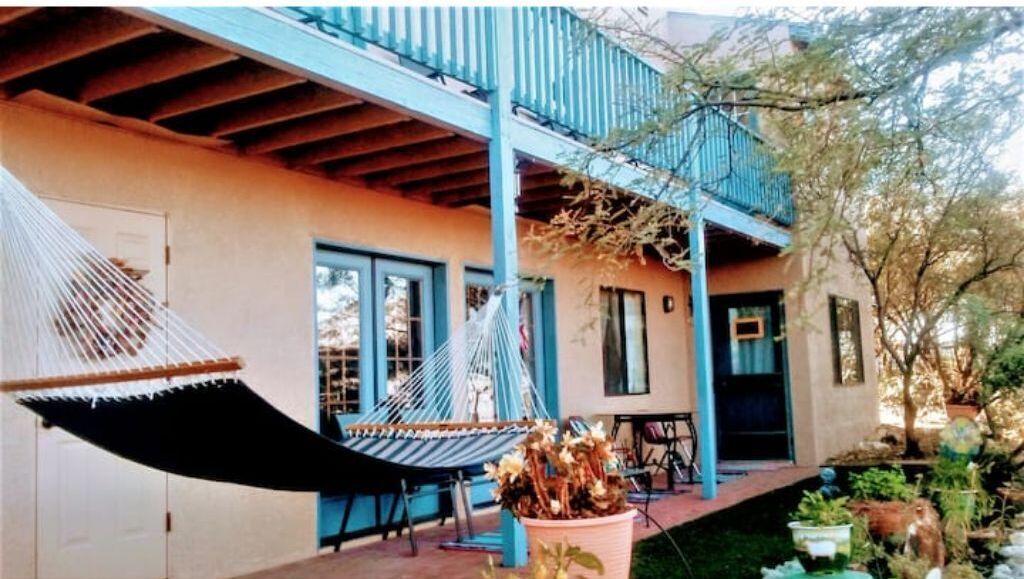 A house with a porch, a hammock, and potted plants.
