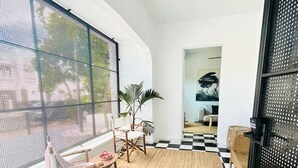 Un interior moderno con piso a cuadros, un ventilador de techo y un ventanal con vistas a la vegetación.