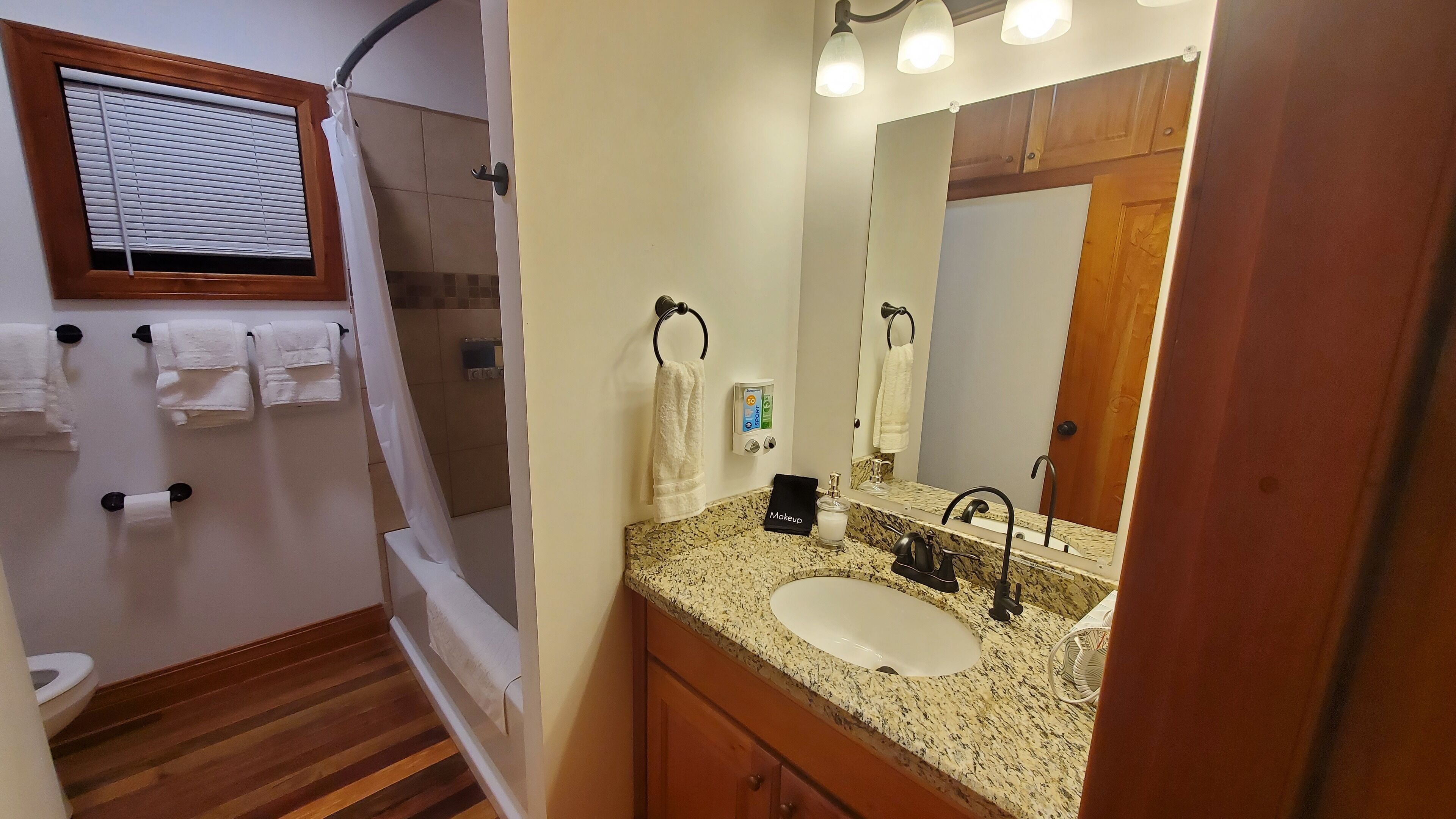 A bathroom with a sink, mirror, towel rack, and shower.
