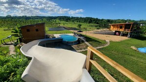 Un patio trasero con piscina, un tobogán y una terraza de madera.