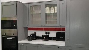 Una cocina con gabinetes grises, microondas, horno, cafetera y tostadora.