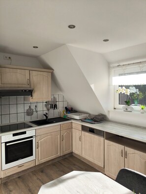 A kitchen with wooden cabinets, a built-in oven, a sink, and a window with a view.