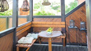 Eine Holzterrasse mit einer Bank, einem Tisch mit einer Vase und hängenden Laternen.