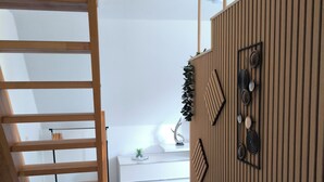 Ein modernes Interieur mit einer Holztreppe, einem weißen Sofa und einer Wandverkleidung.