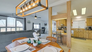 Uma sala de estar moderna com área de jantar, cozinha e janelas amplas.