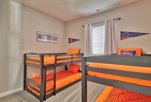 A room with bunk beds, a framed picture on the wall, and two pennant flags.
