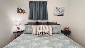 A bedroom with a bed, a nightstand, a lamp, and artwork on the walls. - Hot Tub-Dog & Kid Friendly-FREE digital guidebook! (Rockport)
