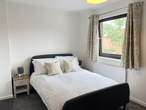 Cozy retreat with a neatly made bed, bedside table, and radiator.