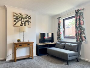 Relax in this stylish living room with a flat-screen TV, comfortable sofa, and beautiful botanical print.