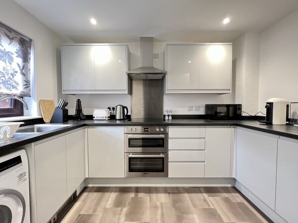 Enjoy cooking in this well-equipped kitchen with a stainless steel range hood, oven, and sink with a dish drying rack.