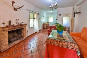 Uma sala de estar com lareira, uma área de refeições e uma cozinha visível ao fundo.