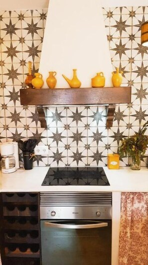 Uma cozinha com design moderno, destacando um mosaico de azulejos, forno embutido e bancada com diversos utensílios.