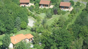 Tre case con tetti rossi, immerse nel verde, collegate da un sentiero sinuoso.