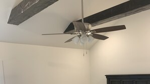 Una camera da letto con un letto, una panca, una ventola a soffitto, un comodino e una lampada.