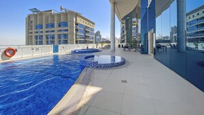 A rooftop swimming pool with a tiled edge, surrounded by modern buildings and a clear sky. - Spacious 2 BD in JLT with Marina Views (Dubai)