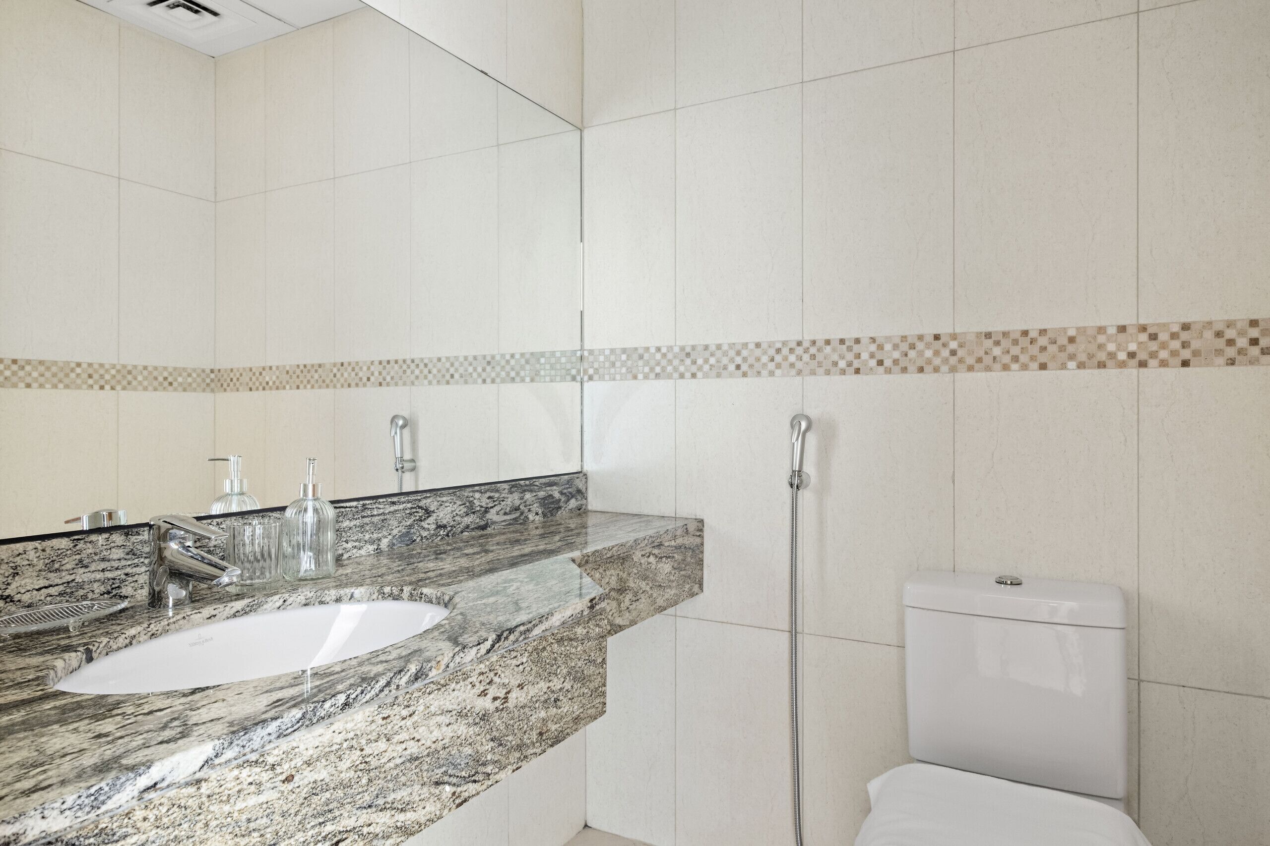Une salle de bain avec un lavabo en marbre, un miroir et des toilettes.