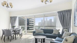 A modern living room with a dining area, large windows, and a city view. - Spacious 2 BD in JLT with Marina Views (Dubai)