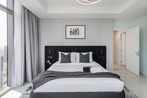 Quarto de hotel moderno com uma cama grande, vista para a cidade, uma obra de arte emoldurada na parede e design minimalista.